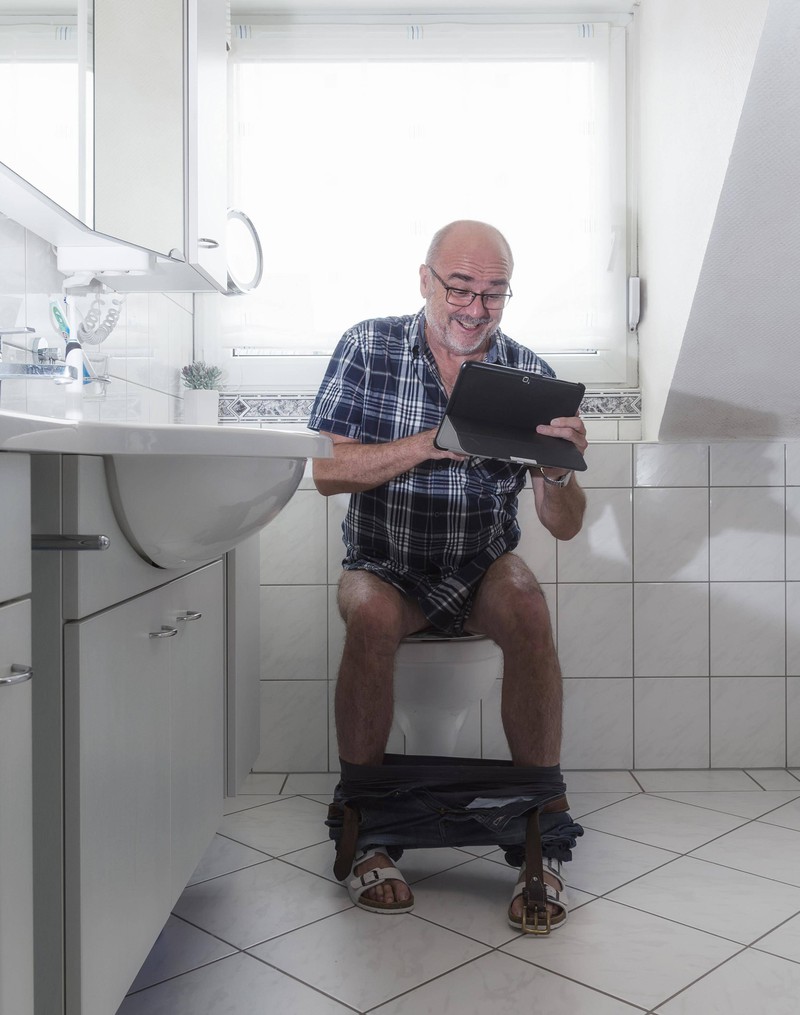 Ein Mann schaut auf der Toilette ein Video