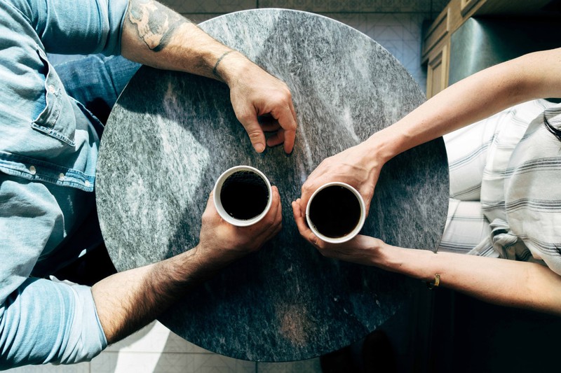 Mann- und Fraunehand mit Kaffee