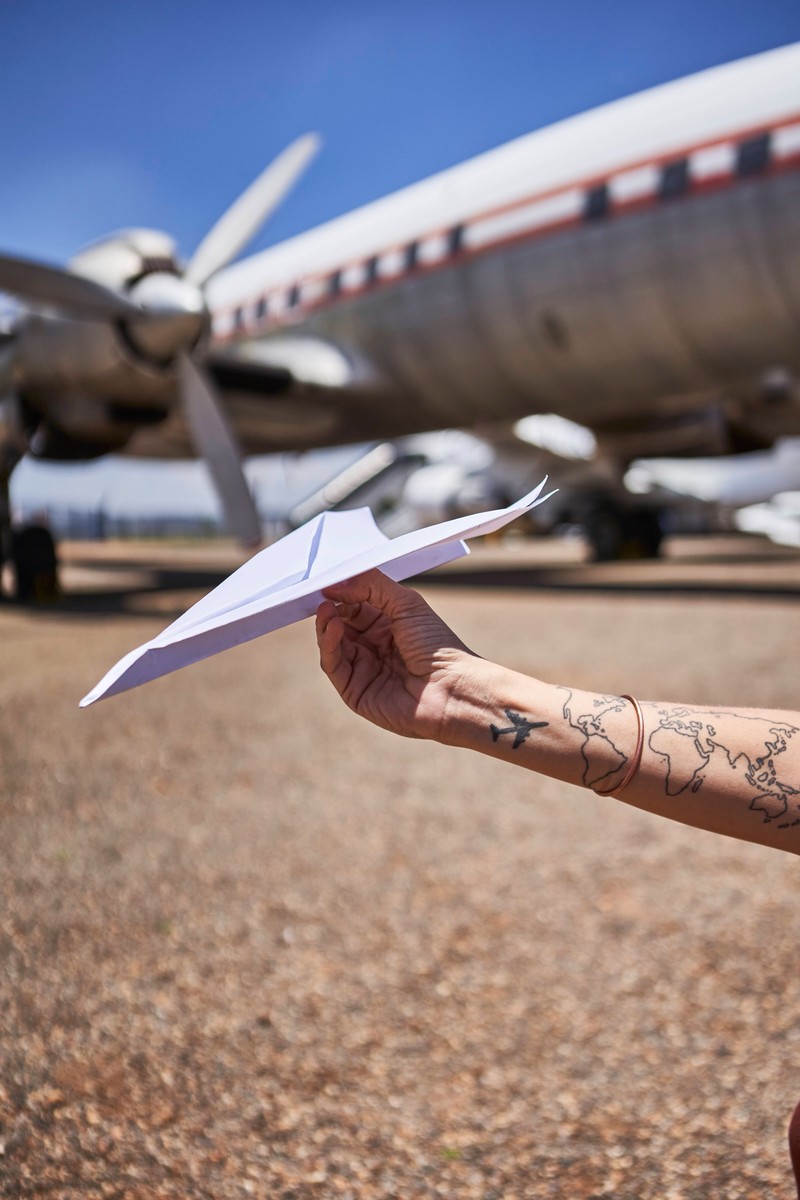 Ein Mann hat einen kleinen Papierflieger auf seinen Arm tätowiert