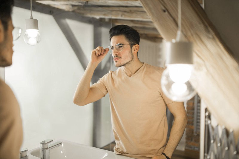 Man sieht einen Mann mit Brille, der womöglich eine Augencreme verwendet