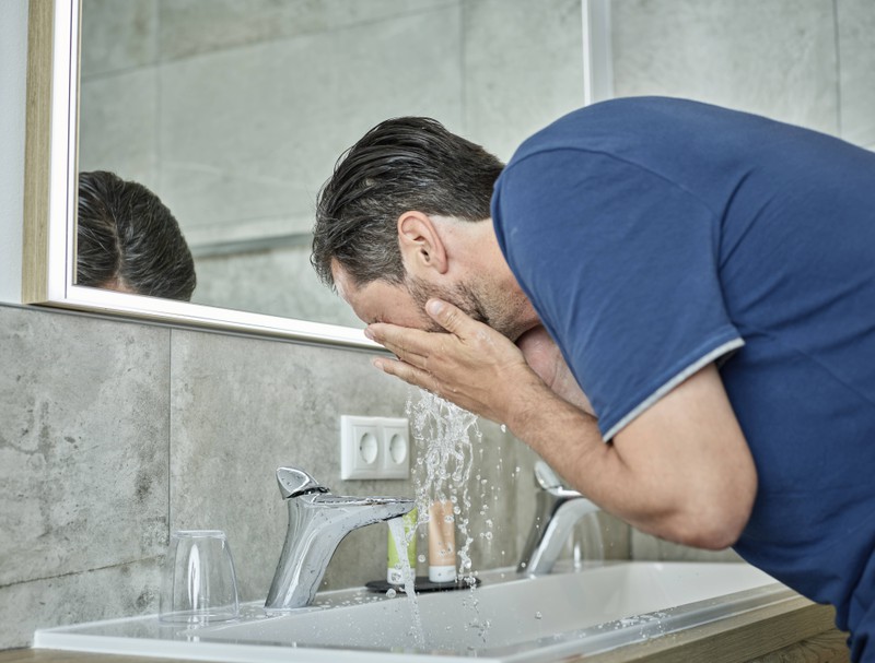 Man sieht einen Mann, der sein Gesicht nur mit Wasser und Seife wäscht, was ein Fehler ist
