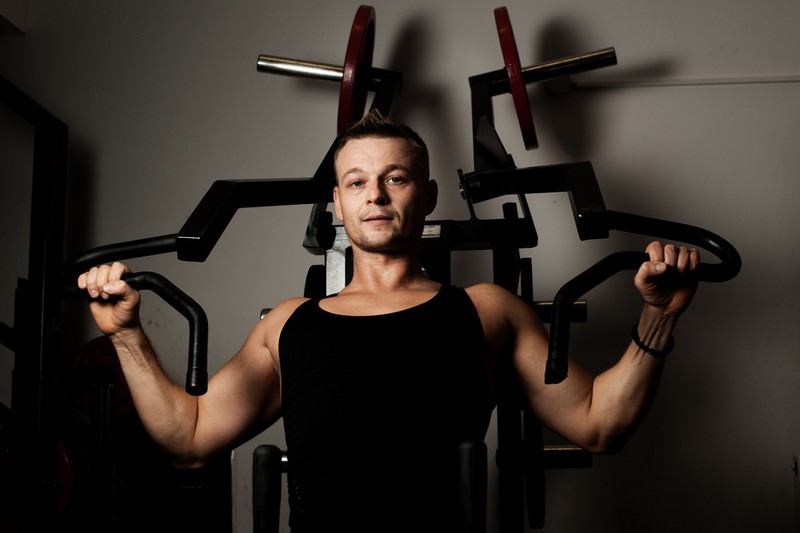 Zu sehen ist ein Mann, der im Fitnessstudio trainiert, um Muskeln aufzubauen.