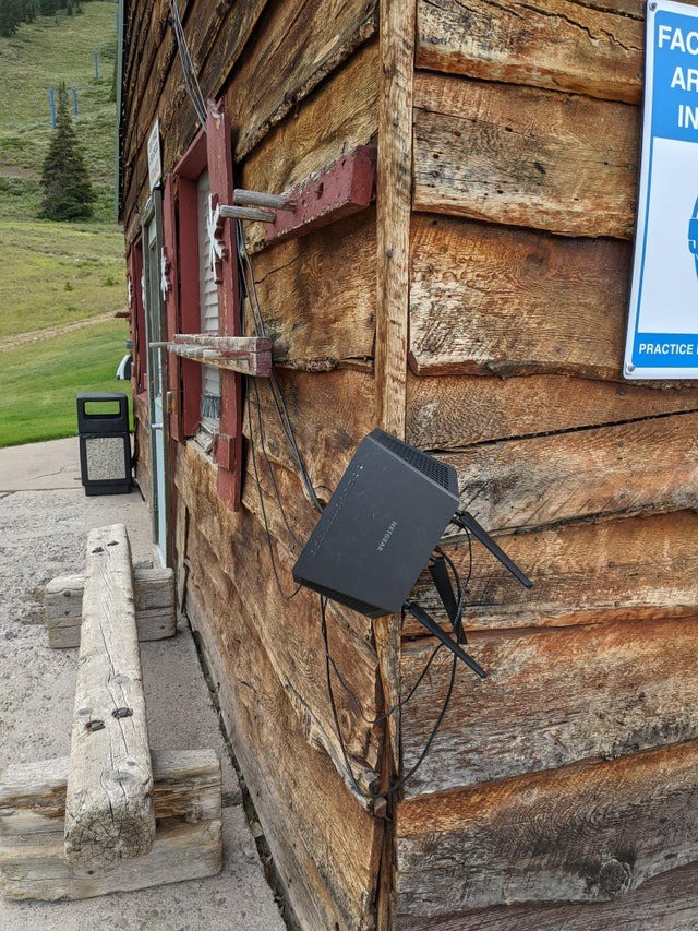 Ein WLAN-Rounter hängt draußen an einer Holzhütte