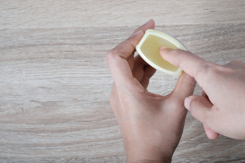 Ein Finger dippt in eine Packung Salbe, da betäubende Salben ein Tipp sind, der Männer im Bett helfen kann