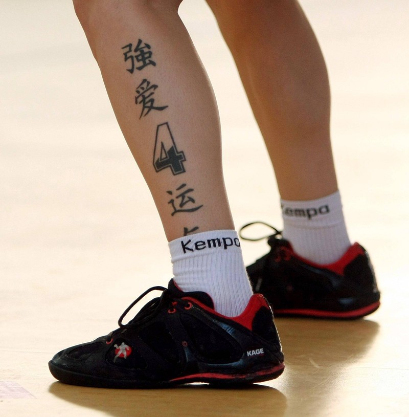 Beine eines tätowierten Mannes, mit chinesischen Schriftzeichen und Symbolen geschmückt